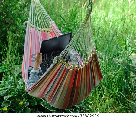 Man in hammock working on his laptop. Concept of a working vacation.