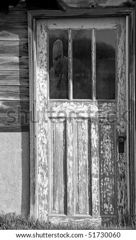 Ghost in an old farmhouse door  window, desaturated.