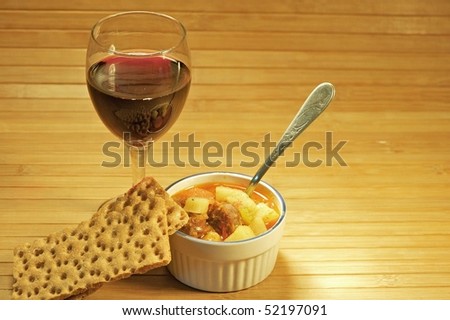 Spicy potato and sausage soup with red wine and crackers.