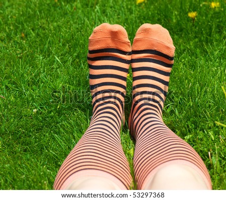 A teenager lays in the grass with her funky socks on with room for your text.