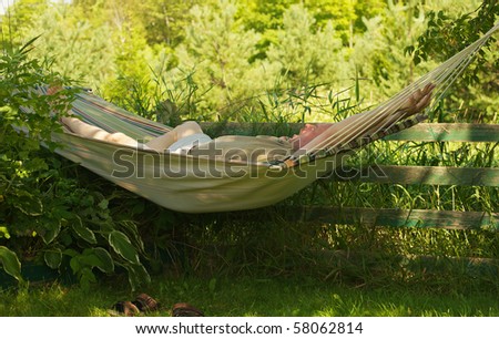 Middle aged man relaxing in a hammock in the shade on a hot summer day.