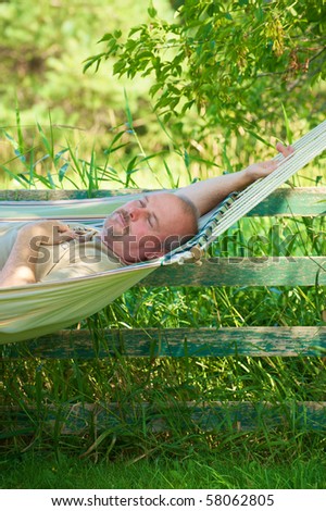 Close up image of a man relaxing in the shade in a hammock on a hot summer day.