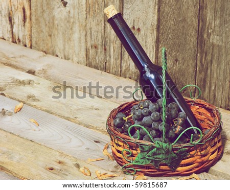Red wine and a basket of freshly picked organic red grapes on a rustic barn board background with copy space.