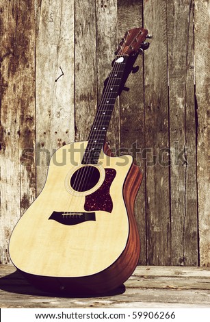 Acoustic guitar leaning against a barn in the sunshine with copy space.