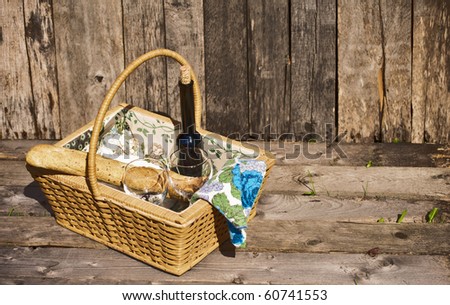 Picnic for two with wine, bread and cheese, on a grunge wood backdrop.