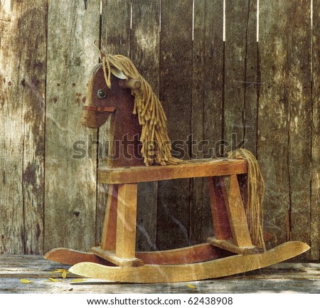 Old rocking horse in the partial shade on a rustic country backdrop.  Grunge textured.