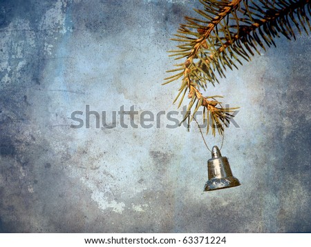Christmas silver bell hanging from a pine branch with copy space.  Grunge textured.