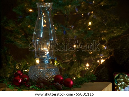 Christmas scene featuring a lit oil lamp on a table in front of a Christmas tree with sparkling lights.