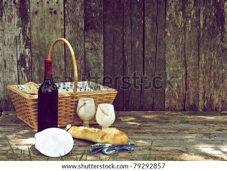 A picnic  for two with wine, bread and cheese in a ceramic holder on a wooden background.