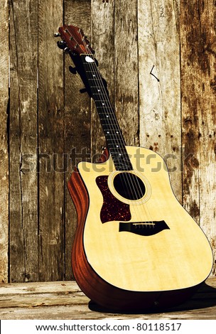 Acoustic guitar on a grunge wood backdrop in the sunshine with copy space.