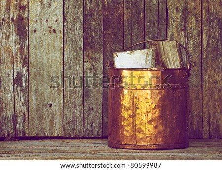 Antique copper wood bucket with wood on a grunge background with copy space.