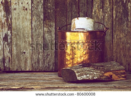 Antique copper wood bucket with wood on a grunge background with copy space.