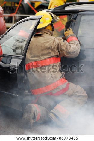 Fireman at the scene of a car accident on a dark rainy day.  Part of a series.