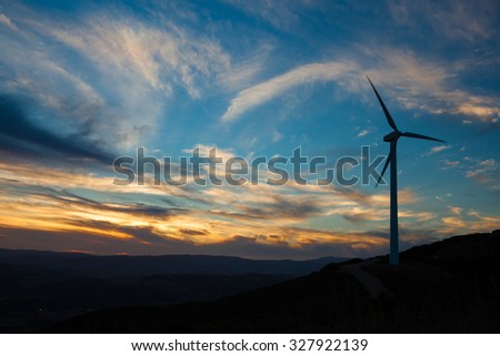 A solitary Wind Turbine silhouetted against a dramatic sunset sky. Landscape Format