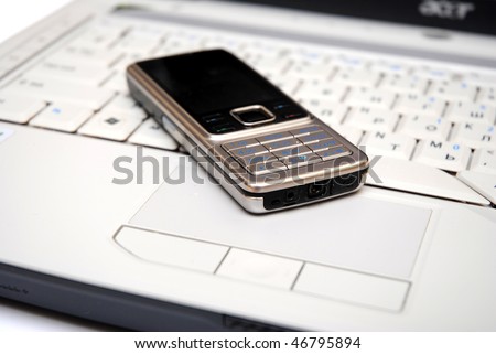 silver mobile phone on grey laptop