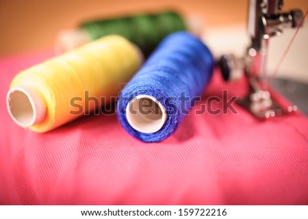 Close up of threads on fabric and sewing machine. Selective focus. Focus on blue threads.