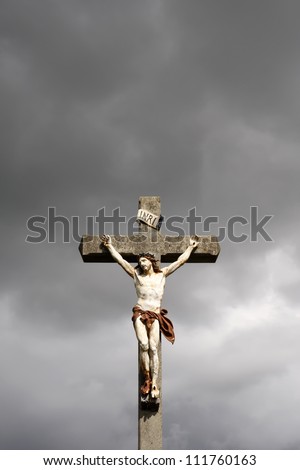 Jesus Christ crucifixion sculpture against dark clouds