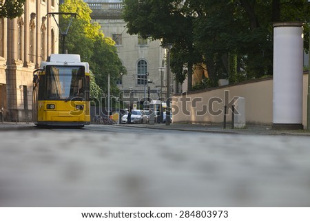Yellow tram on the street with advertising pillar