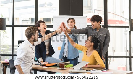 Group of five creative workers giving each other high-five with big smile on face, successful team performance, finishing touch