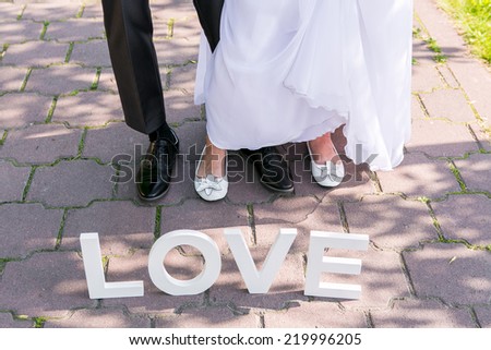 Feet of groom and bride and white love letters