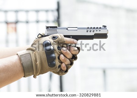 Hands with brown gloves holding pistol handgun
