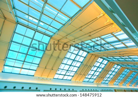 underside wide angled and perspective view to steel blue glass airport ceiling through high rise building skyscrapers, business concept of successful industrial architecture