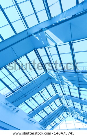 underside wide angled and perspective view to steel blue glass airport ceiling through high rise building skyscrapers, business concept of successful industrial architecture