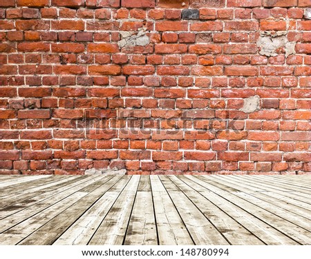 Grungy textured red brick and stone wall with warm brown wooden floor inside old neglected and deserted interior, masonry and carpentry brickwork concept