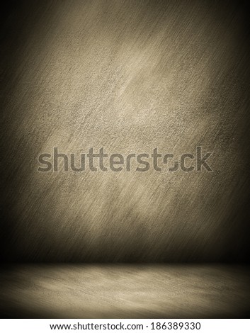 Abstract stonework background texture of an old weathered dark stucco black painted stone cement wall in rural room. Grungy golden rock surface in hard grime empty place with brown dull light floor.