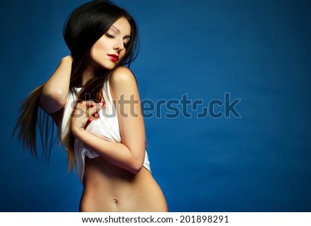 Portrait of beauty attractive fashion slim healthy young woman dancing with perfect training sexy tanned skin sport body in an ideal white and red lingerie on dark blue background
