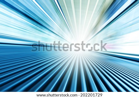 Perspective wide angle view of modern metal chrome and light blue illuminated airport, spacious high-speed technology moving escalator, fast blurred trail of steel handrail in vanishing traffic motion