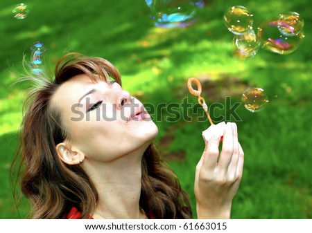 attractive girl inflating soap bubbles