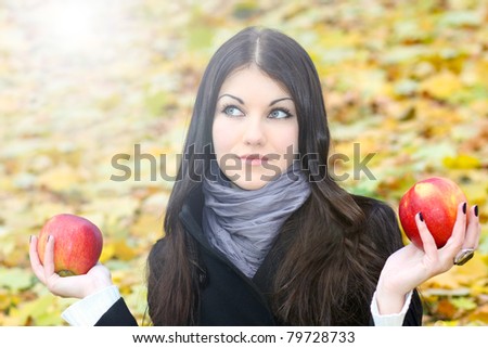 portrait of the dreaming gorgeous woman hesitated with two bright fresh red apples