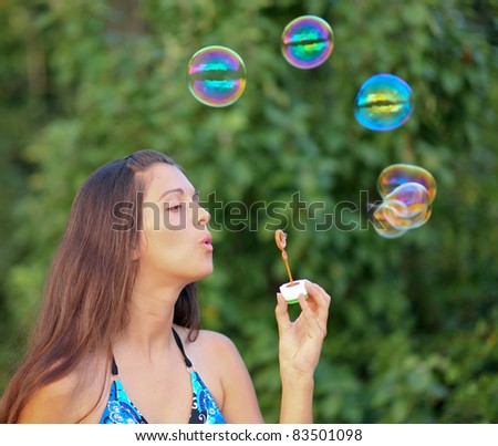 Young girl inflating colorful soap bubbles