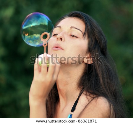 Pretty girl inflating soap-bubbles