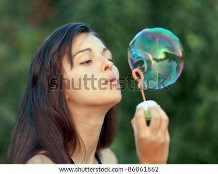 Adorable woman inflating soap-bubbles