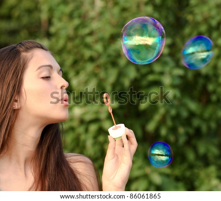 Alluring woman inflating soap-bubbles