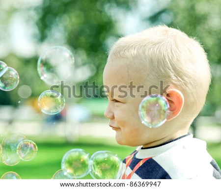 Beautiful little boy inflating soap bubbles
