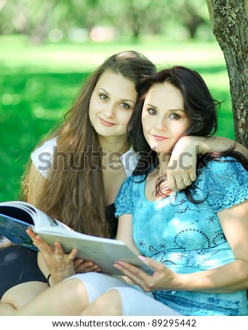 beautiful mother and daughter reading fairy book in nature