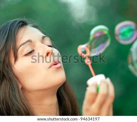 Attractive woman inflating soap-bubbles