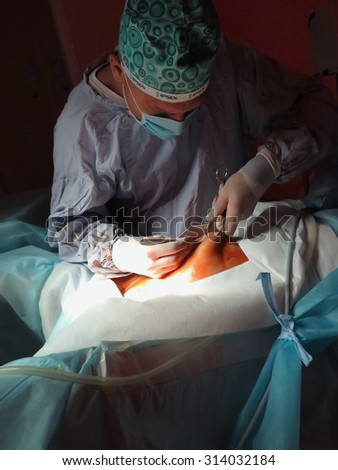 Odessa, Ukraine - October 9th, 2014 :The surgeon makes an incision in the abdomen for surgery in the operating room.  increasing worldwide demand for services of surgeon