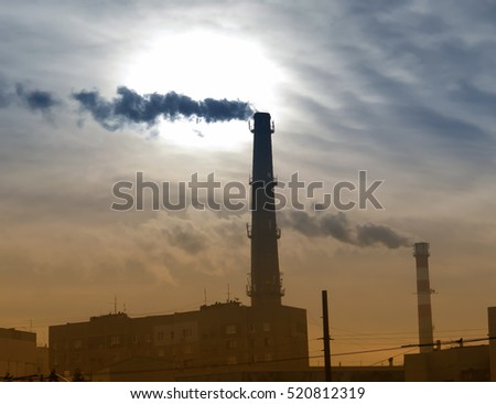 Smoking chimney at sunset on industrial buildings complex with vintage and blur effect.