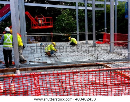 Rebars are laid. Shear studs are welded to the top flange of the steel section through metal deck. Workers are installing the threaded rods which are used with metal strut to suspend from ceiling.