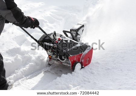 Man removing snow after storm with a snow-blower