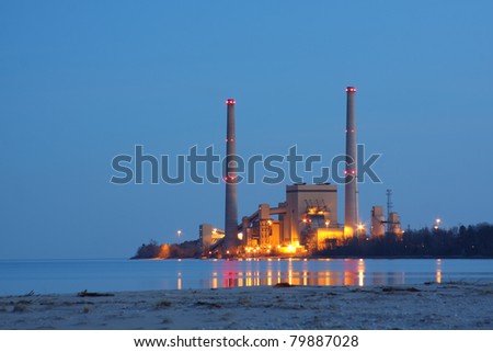 Coal power station by a lake in the evening reflecting in the water