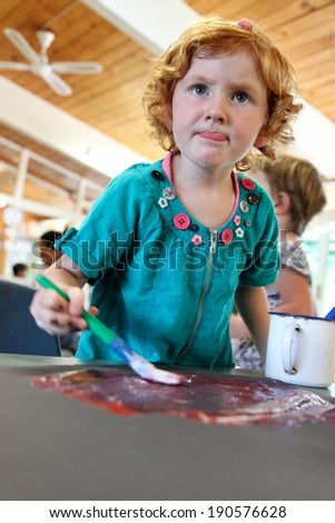 little red headed girl painting a picture during her preschool kindergarten class