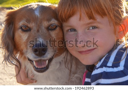 back lit portrait of redheaded girl with red haired dog hugging