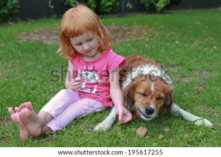 red headed girl with red haired dog eating dog biscuits