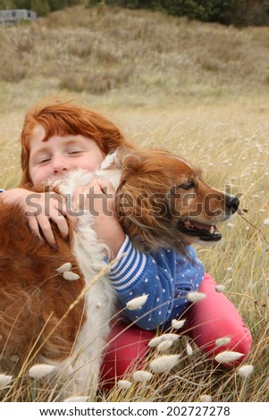 red haired girl with red collie type dog in a beach side meadow