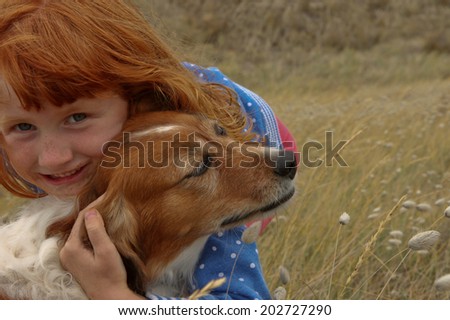 red haired girl with red collie type dog in a beach side meadow